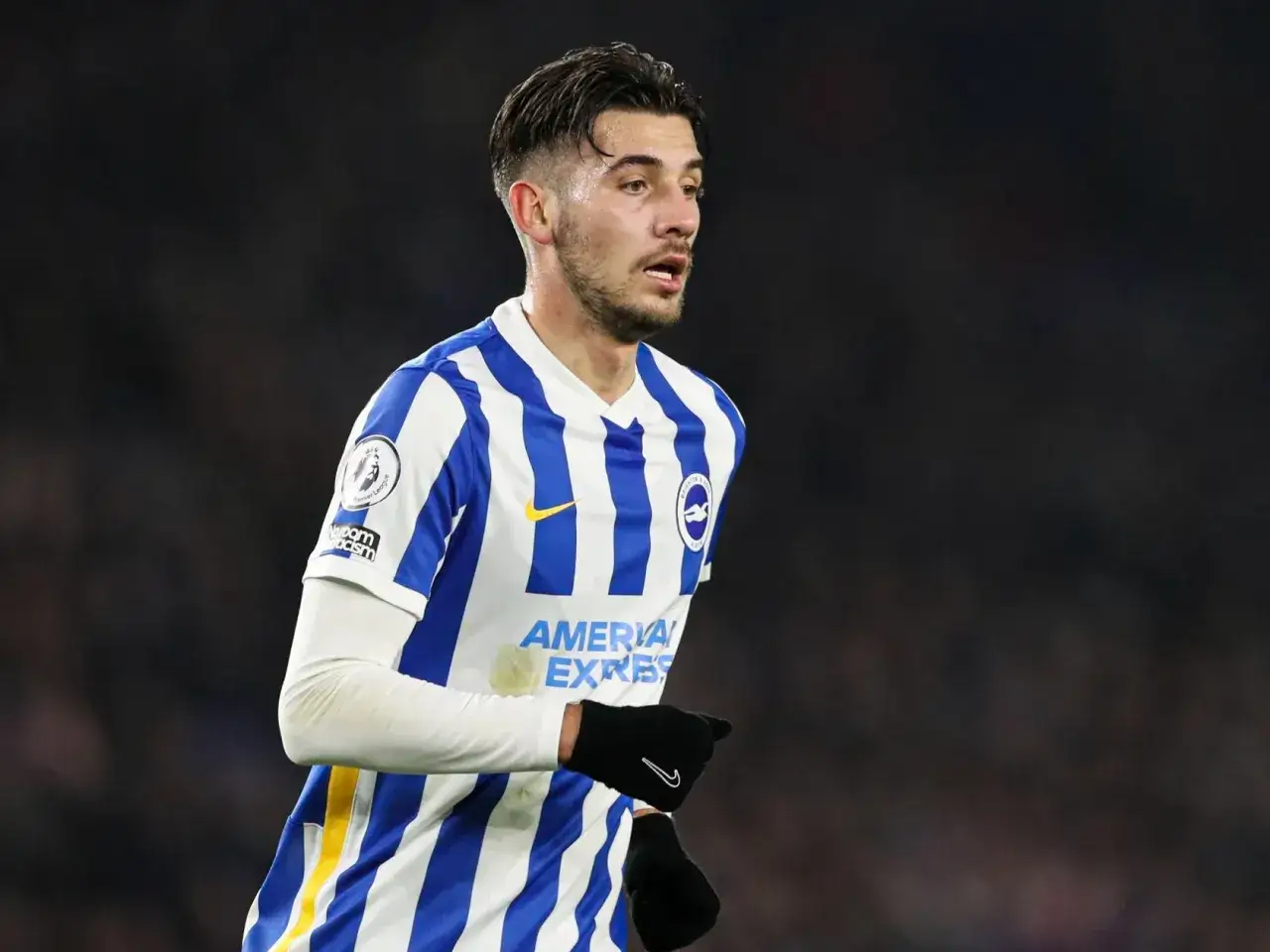 Piłkarz Jakub Moder w koszulce Brighton, zmagający się z kontuzją, na tle trybun.