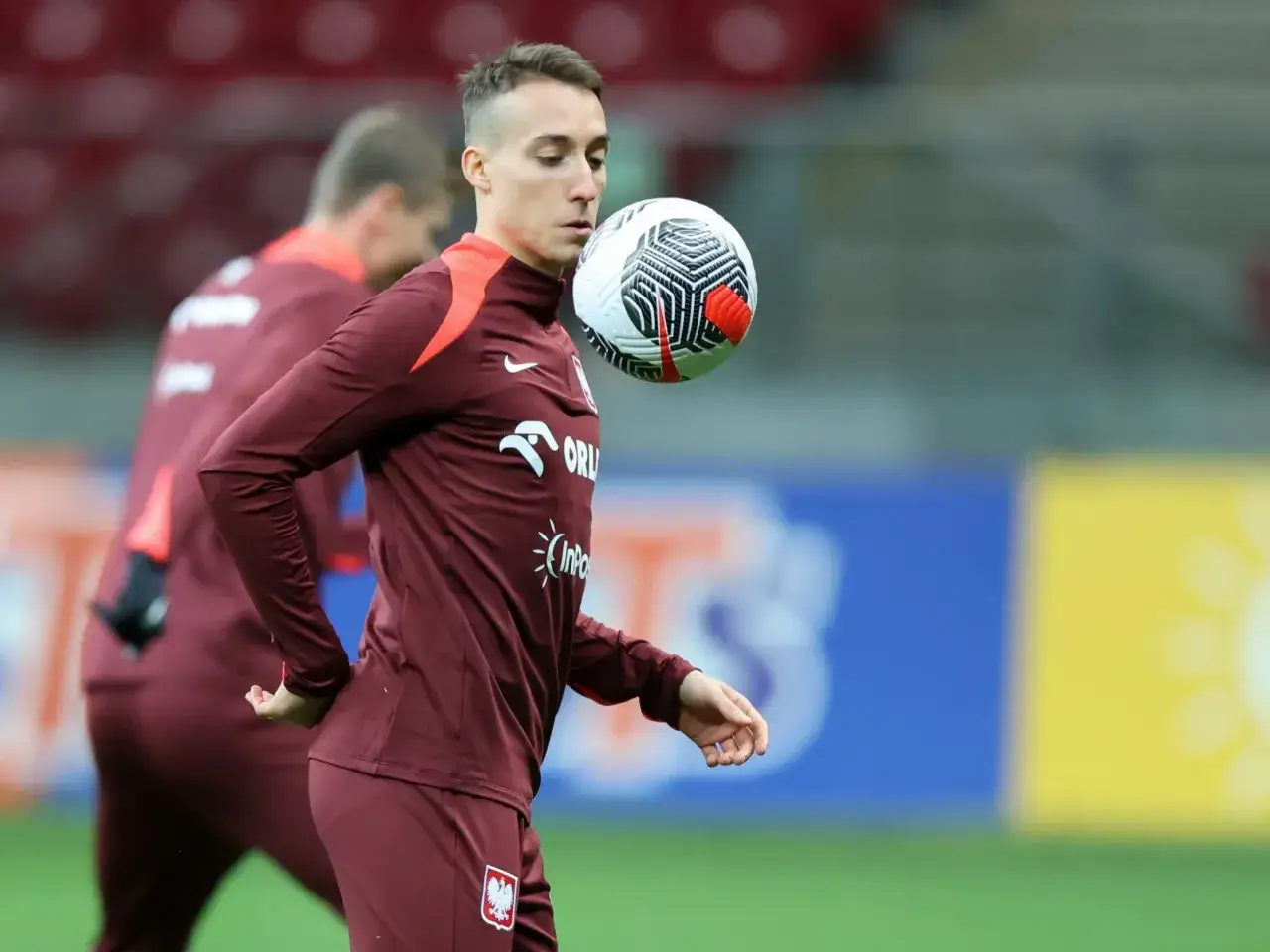 Dominik Marczuk ćwiczy drybling z piłką na boisku.