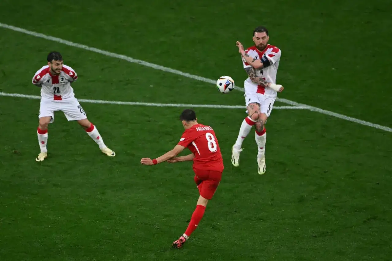 Arda Güler w czerwonej koszulce z numerem 8 strzela gola, podczas gdy przeciwnik próbuje go zablokować.