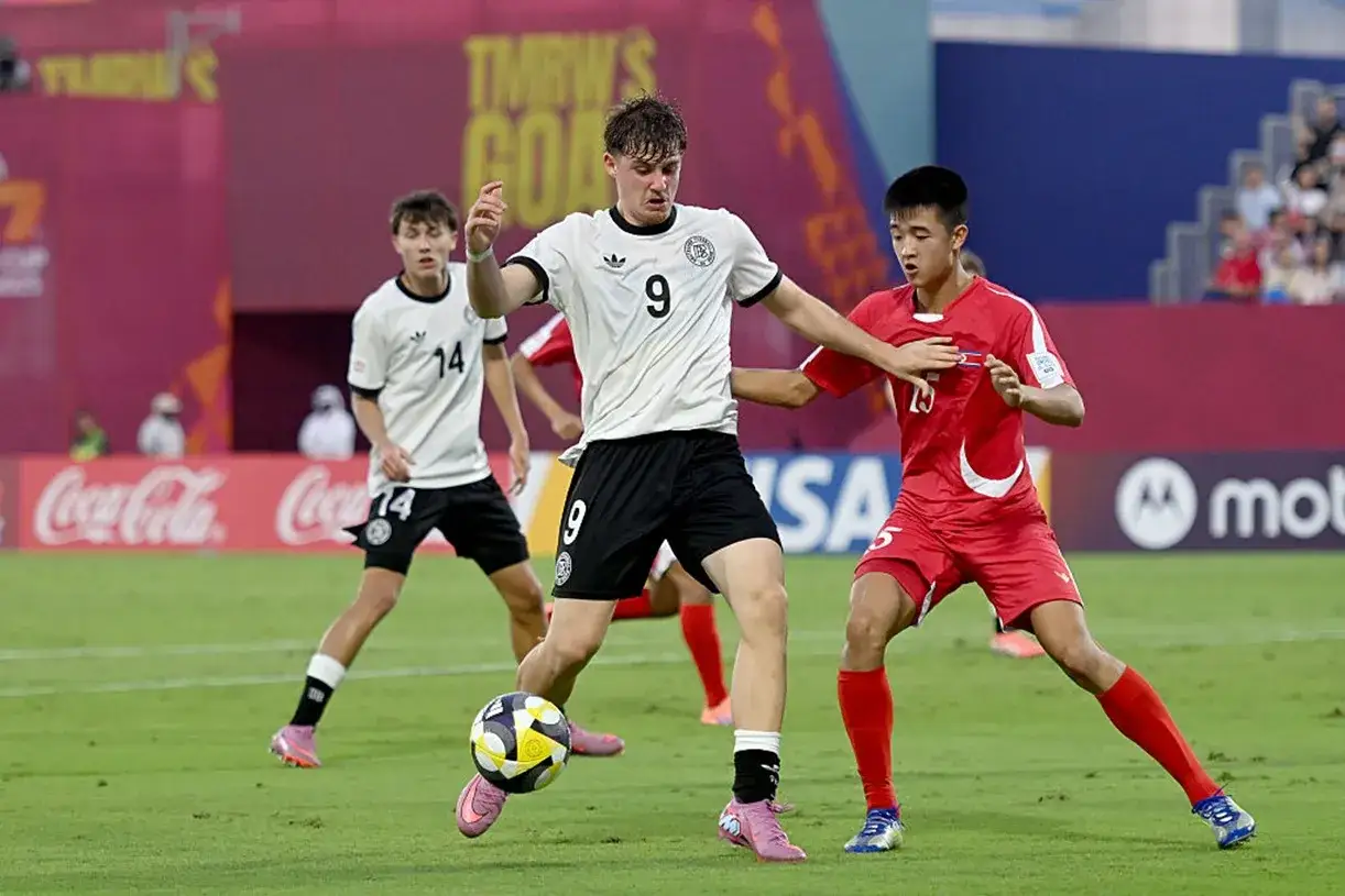 Piłkarze Niemiec i Korea P&oacute;łnocna walczą o piłkę podczas meczu.