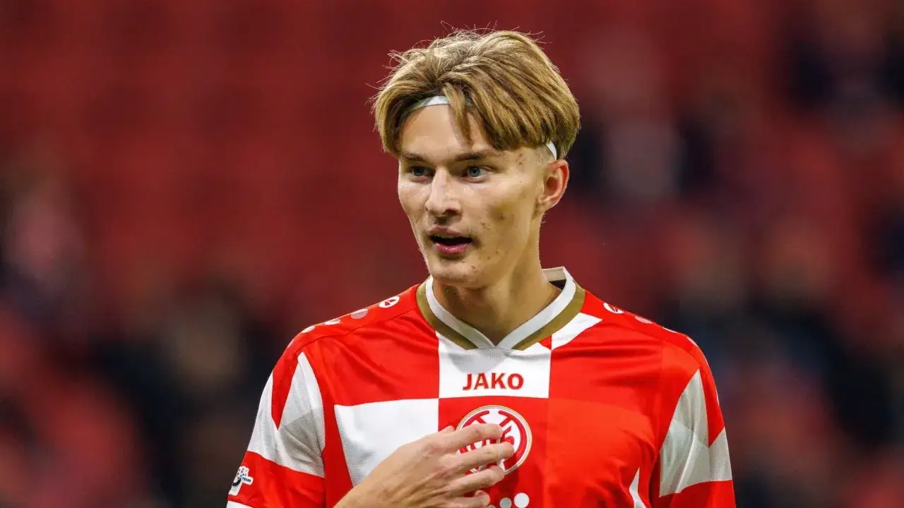 Młody zawodnik Bundesligi w czerwono-białej koszulce z logo Jako, z opaską na włosach, na tle trybun.