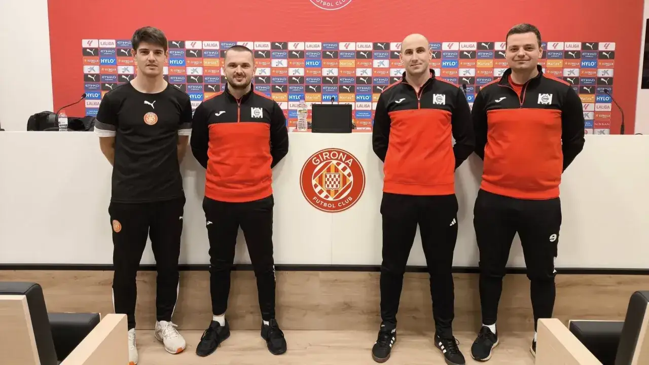 Girona FC – zawodnicy w strojach treningowych pozują do zdjęcia przed ścianką z logo klubu.