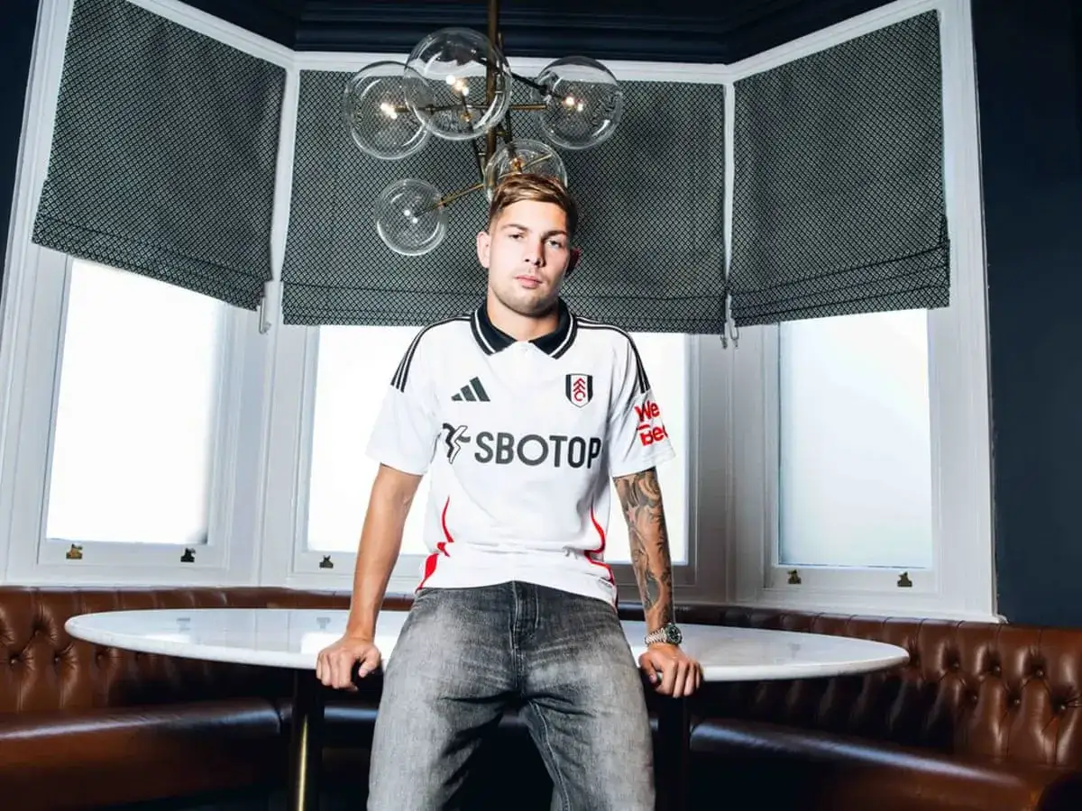 Emile Smith Rowe w nowym stroju Fulham, siedzi przy okrągłym stole.