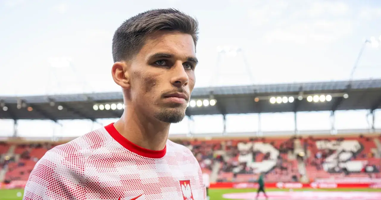 Filip Marchwiński w biało-czerwonej koszulce z godłem Polski, na tle stadionu.