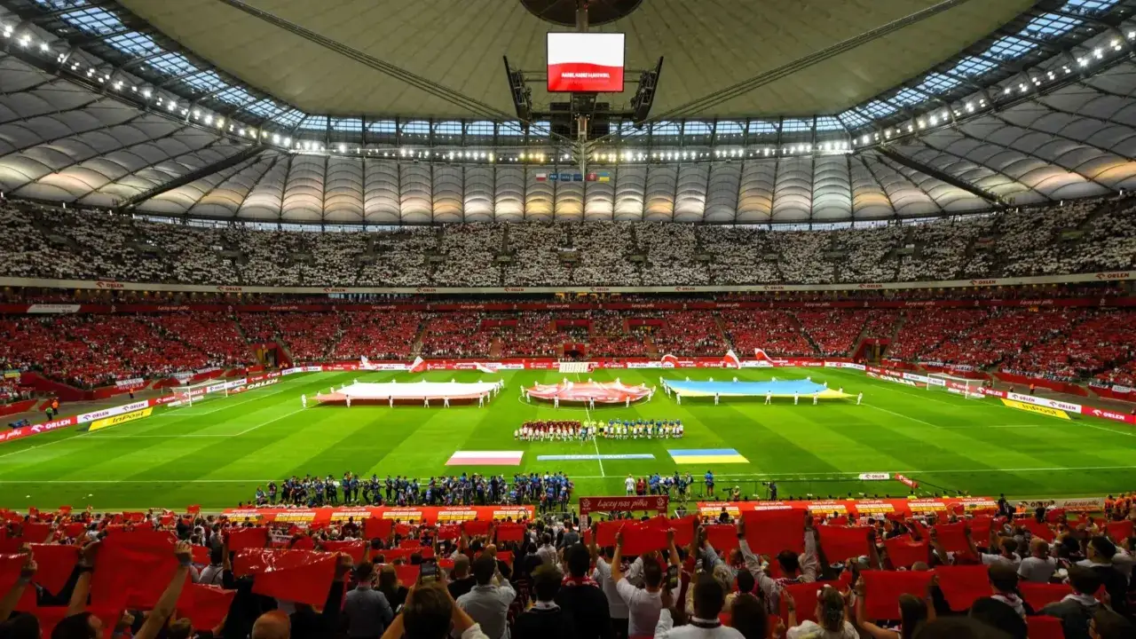 Stadion wypełniony kibicami w biało-czerwonych barwach. Na murawie rozłożone flagi Polski i Ukrainy. Rozgrywki i liga w pełnym blasku.
