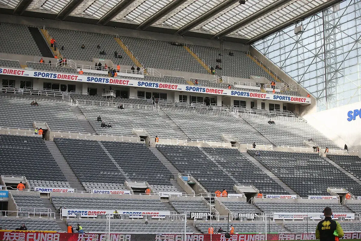 Puste trybuny stadionu St James' Park, z widocznymi banerami reklamowymi.