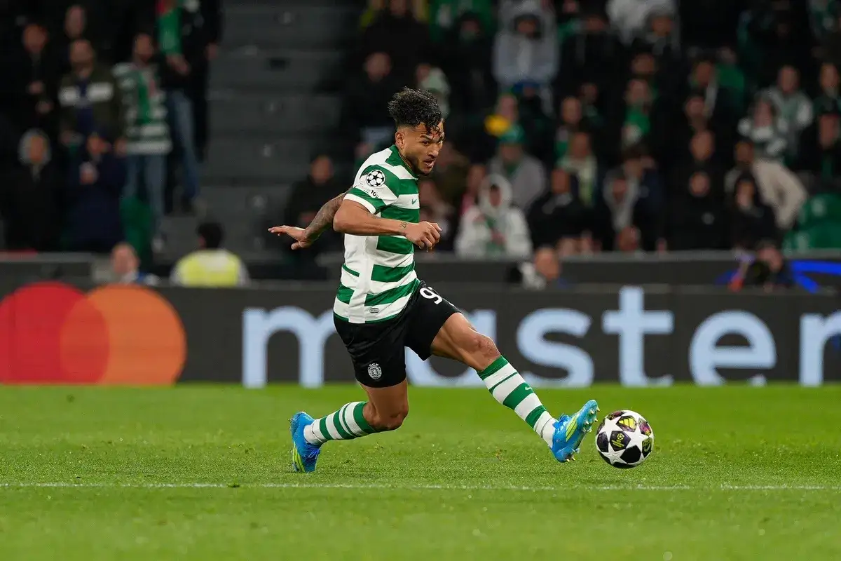 Piłkarz Sporting CP w zielono-białej koszulce drybluje z piłką na boisku podczas meczu Estrela Amadora – Sporting CP.