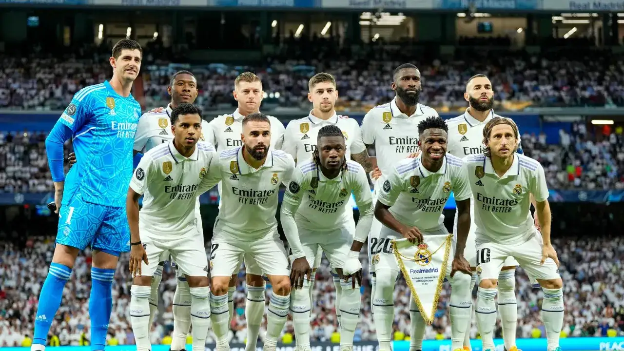 Real Madryt - skład. Drużyna w białych strojach, bramkarz w niebieskim. Na pierwszym planie Modrić, Vinícius, Camavinga, Rüdiger, Benzema.