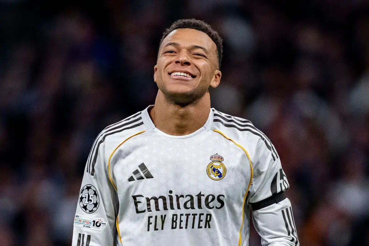 Uśmiechnięty piłkarz w białej koszulce Realu Madryt, z herbem klubu i logo Emirates. To kluczowy zawodnik w podstawowy skład Realu Madryt.