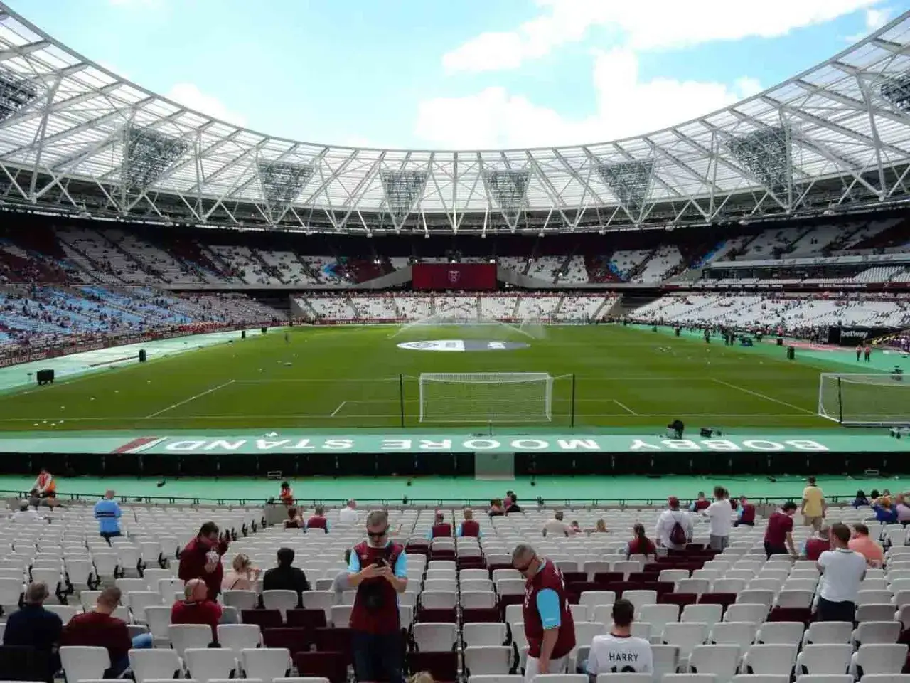 Widok na murawę i trybuny stadionu West Ham. Na zielonym pasie widać napis 