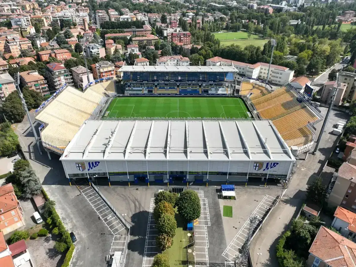 Widok z lotu ptaka na stadio Ennio Tardini z zieloną murawą i żółtymi trybunami.