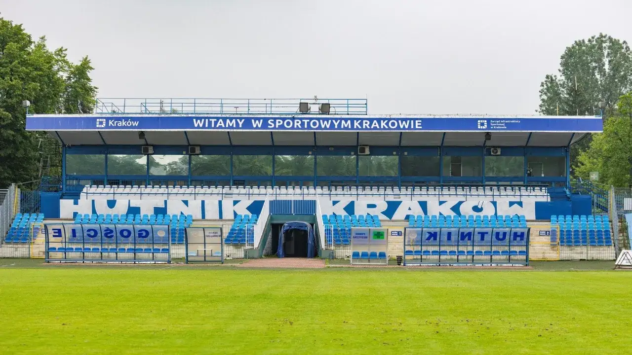 Stadion Hutnik Kraków z niebieskimi siedzeniami i napisem