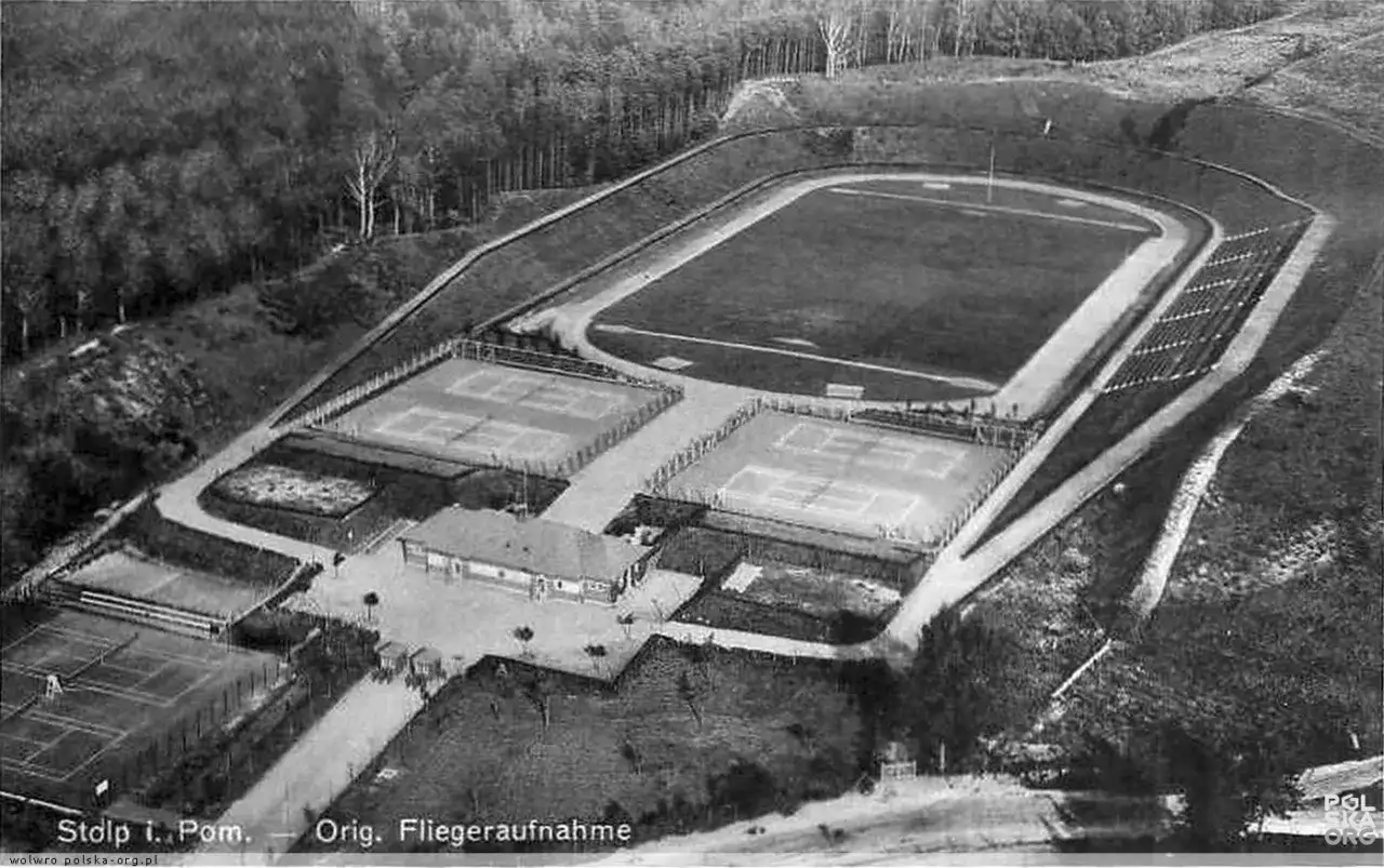 Stadion 650-lecia Słupsk z bieżnią, kortami tenisowymi i budynkiem klubowym, otoczony lasem.